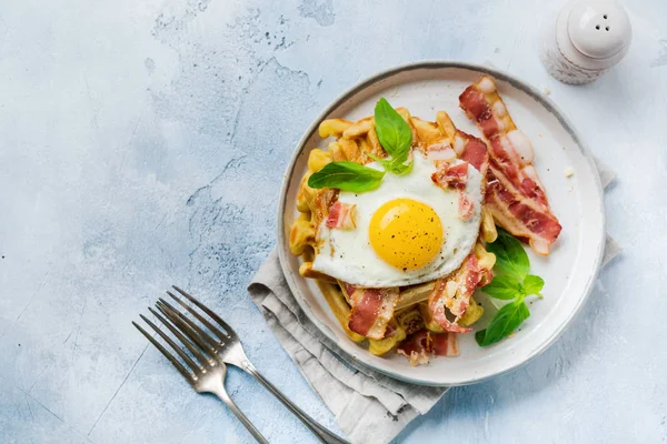 Hafif eski beton arka plan üzerinde kahvaltı için kızarmış pastırma, yumurta ve baharat ve fesleğen ile parmesan peyniri ile Peynir Waffle. Üstte görüntü.