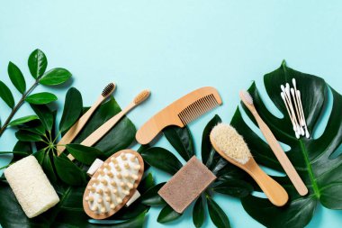 Çevre dostu banyo aksesuarları ya da mavi arka plandaki yapraklar üzerindeki spa aletleri. Kozmetik beton arka plan. Güzellik ve sıfır atık kavramı.