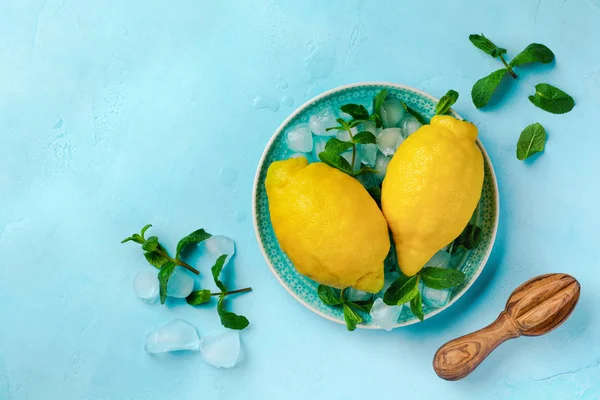 Two fresh lemons in blue plate on turquoise concrete background. Food background. Top view.
