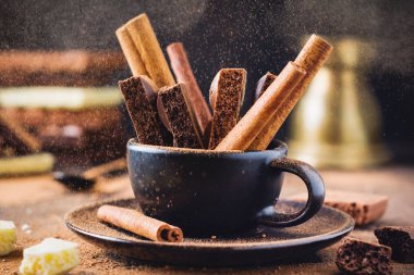 Gözenekli çikolata ve tarçın parçaları koyu eski arka plan üzerinde siyah kahve fincanı sopalarla. Seçici odaklama.