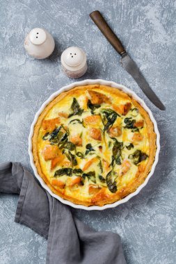 Kırmızı balık ve hafif ahşap zemin üzerine ıspanak ile ev yapımı kiş tart. Vintage tarzı. Üstten Görünüm.