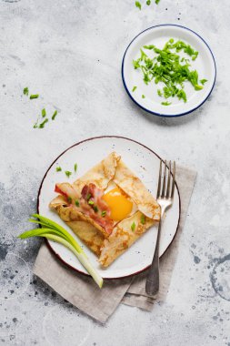 Sahanda yumurta, peynir, pastırma ve yeşil soğan bir ışık gri beton zemin üzerine kahvaltıda krep.
