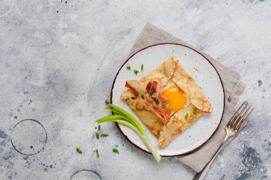 Sahanda yumurta, peynir, pastırma ve yeşil soğan bir ışık gri beton zemin üzerine kahvaltıda krep.