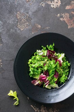 Koyu taş arka plan üzerinde salata için arugula, marul, ıspanak, pancar taze yaprakları karıştırın. Seçici odaklama.