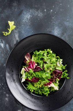 Koyu taş arka plan üzerinde salata için arugula, marul, ıspanak, pancar taze yaprakları karıştırın. Seçici odaklama.