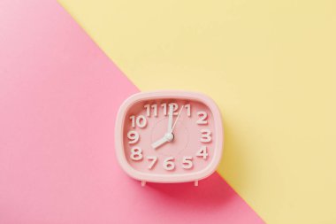 Pembe çalar saat sarı yüzey zemin üzerine yalan. Üstten görünüm. 
