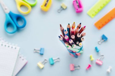 Renkli kalemler, makas, defter, cetvel, kalem, silgi, keskinleştirme ve cam daha fazla. Açık mavi arka plan üzerinde okul ve ofis kırtasiye. Kavram okula geri döndü. Üstte görüntü.