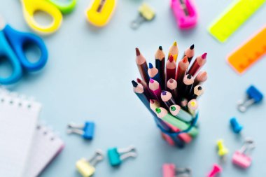 Renkli kalemler, makas, defter, cetvel, kalem, silgi, keskinleştirme ve cam daha fazla. Açık mavi arka plan üzerinde okul ve ofis kırtasiye. Kavram okula geri döndü. Üstte görüntü.