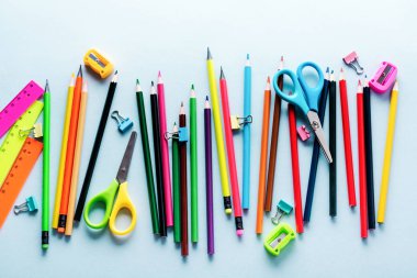 Renkli kalemler, makas, defter, cetvel, kalem, silgi, keskinleştirme ve cam daha fazla. Açık mavi arka plan üzerinde okul ve ofis kırtasiye. Kavram okula geri döndü. Üstte görüntü.