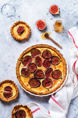 İncirli ev yapımı kiş turtası, krem peynir ve arkaplanda bal. Eski tarz. Üst görünüm.