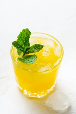 Bir bardak nane yapraklı portakal suyu ve beyaz taşralı arka planda buz. Seçici odak. 