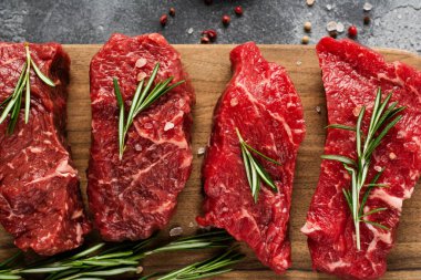 Baharatlı, soğanlı ve biberiyeli çiğ biftek. Koyu levha ya da beton arka plan. Üst görünüm