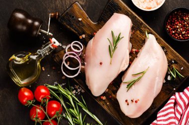 Taze çiğ tavuk fileto ile tuz, biber, soğan ve tereyağı ile ahşap bir tahta üzerinde koyu ahşap arka planda. Üst görünüm.