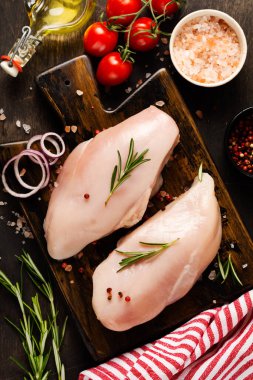Taze çiğ tavuk fileto ile tuz, biber, soğan ve tereyağı ile ahşap bir tahta üzerinde koyu ahşap arka planda. Üst görünüm.