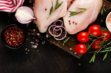 Taze çiğ tavuk fileto ile tuz, biber, soğan ve tereyağı ile ahşap bir tahta üzerinde koyu ahşap arka planda. Üst görünüm.