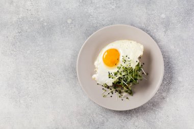 Geleneksel İngiliz kahvaltısı roka yumurtalı, gri seramik tabakta gri beton arka planda. Üst görünüm.