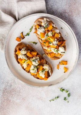 Fırınlanmış balkabağı sandviçi, mavi küflü Dorblu peynirli, bal ve kekik, beton, eski, aydınlık arka planda. Üst görünüm.