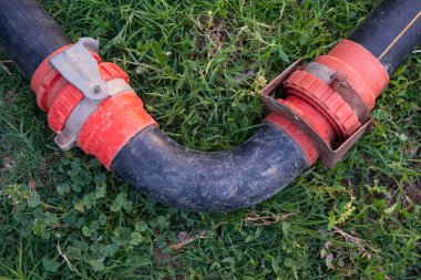 Bahçedeki turuncu kavisli sulama borusu..