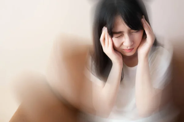 Evde kanepede otururken baş dönmesi, baş dönmesi ve baş ağrısı çeken genç bir kadın. Baş dönmesi, baş dönmesi, stres, felç, menieres hastalığı ya da beyin tümörü. Sağlık sorunları.