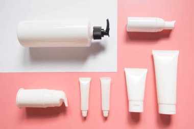 Kozmetik ürünler koleksiyonu. Pembe ve beyaz arka planda boş bir kozmetik şişe / tüp. Losyon, krem, jöle, köpük, sabun ya da şampuan için marka modeli. Asgari düzeyde. Güzellik blogcusu kavramı. Üst görünüm.