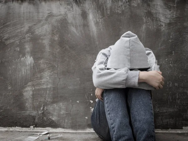 Uyuşturucu bağımlılığı ve yoksunluk belirtileri konsepti. Depresyonda ve umutsuz genç kız terk edilmiş evde uyuşturucu ve alkol aldıktan sonra yalnız oturuyor. Uyuşturucu Bağımlılığına Karşı Uluslararası Gün.