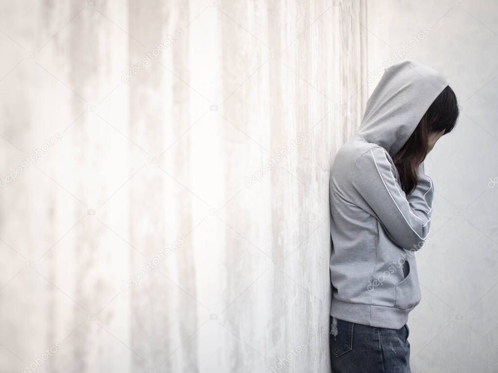 Drugs addiction and mental withdrawal symptoms concept. Depressed woman crying and leaning against grunge concrete wall after using drugs or alcohol. International Day against Drug Abuse. Copy space.