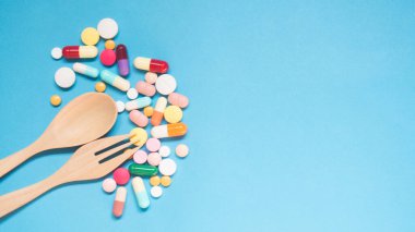 İlaç haplarının, kapsüllerin ve tabletlerin açık mavi arka planda tahta kaşıkla en üst görüntüsü. Vitamin ve takviye. Sağlık davranış konsepti. Asgari düzeyde. Yaratıcı bir fikir. Boşluğu kopyala.