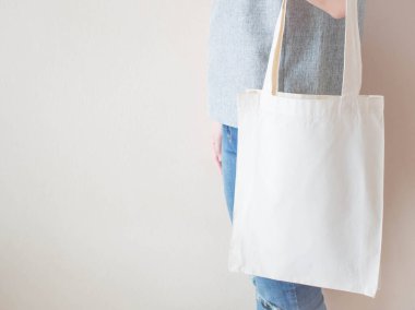 Boş beyaz pamuk çanta ve kabzalı tasarım modeli. Eko ya da tekrar kullanılabilir alışveriş torbası tutan kadına yakın durun. Plastik poşet ve ekoloji konsepti yok. Boşluğu kopyala.