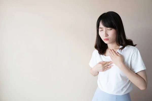 Asit reflüsü ya da Gastroözofageal reflü hastalığı (GERD) kavramı. Genç Asyalı kadın beyaz arka planda mide ekşimesi ya da göğüs ağrısı belirtileri gösteriyor. Sağlık ve tıbbi konsept.
