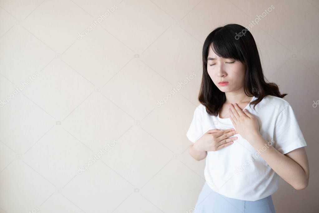 Acid reflux or Gastroesophageal reflux disease (GERD) concept. Young asian female suffering from heartburn or chest discomfort symptoms over white background. Health care and medical concept.