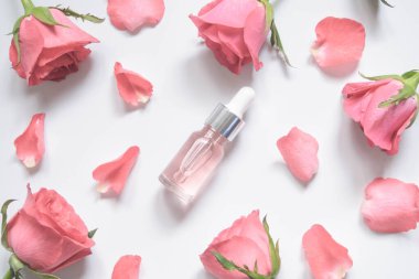 Ev yapımı cilt, doğal gül suyu ve gerekli yağ ürünüdür. Pembe gül ve kozmetik cam şişesi nemlendirici serum, yüz toneri, temizleyici, makyaj çıkarıcı ya da sivilce tedavisi için. Düz Düzen.