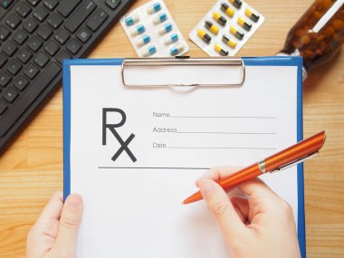 Kadın doktor elleri klavye ve ilaç tabletiyle hastaya reçeteli reçete ya da rX formu tutuyor. Doktorun masasının üst görüntüsü. Sağlık ve Tıp Konsepti.
