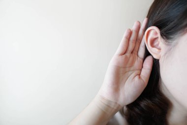 Metnin için beyaz arka plan üzerinde elini kulağına yakın tutan bir kadının fotoğrafını çek. Dedikodu kavramı, ilginç haberler veya duyma kaybı.