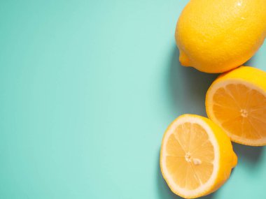 Limon yeşili arka planda taze sarı limon turunçgil meyvesi. Yarısını ve bütün limonları kes. Uzayı kopyala Üst görünüm.