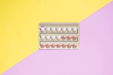 Sarı arka planda doğum kontrol hapları var. Hamileliği önlemek ve PCOS, endometriyozis, amperoz veya sivilce gibi diğer tıbbi durumları tedavi etmek için kullanılan hormonlar. Jinekoloji konsepti.