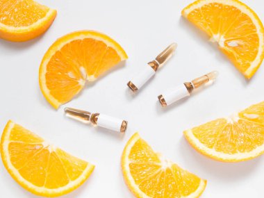 C vitamini kahverengi ampul. Beyaz masada taze portakal suyu slaytları var. Beyaz ten için yüksek dozda C vitamini sentetik. Güzellik ürünleri markası maketi. Sağlıklı bir yaşam tarzı. Üst görünüm.