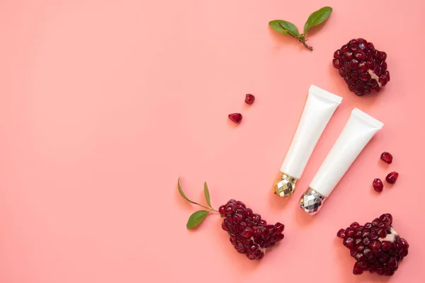 Natural skincare product containing organic pomegranate seed oil extract on pink background. Packaging of eye cream, lip balm, anti-acne gel. Beauty cosmetic mock-up.