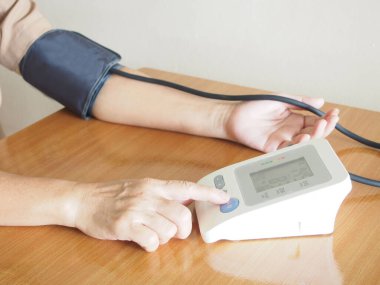 Orta yaşlı kadınlar kan basıncını ve kalp atışlarını evde otomatik tansiyon monitörüyle ölçüyorlar. Sağlık ve Tıp Konsepti.