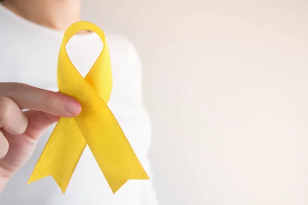 Endometriyozis, intihar önleme, sarkoma kemiği kanseri, mesane kanseri, karaciğer kanseri ve çocukluk kanseri konsepti için sarı altın kurdele farkındalığı sembolü taşıyan genç bir kadın. Sağlık hizmetleri. Boşluğu kopyala.