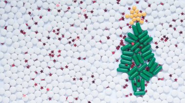 Sağlık, tıbbi ve eczane konsepti için Noel ve Mutlu Yıllar teması. Yeşil Noel ağacı, beyaz kar ve ilaç hapı / kapsül tarafından yapılan dekoratif sarı yıldız. Yaratıcı bir fikir. Boşluğu kopyala.