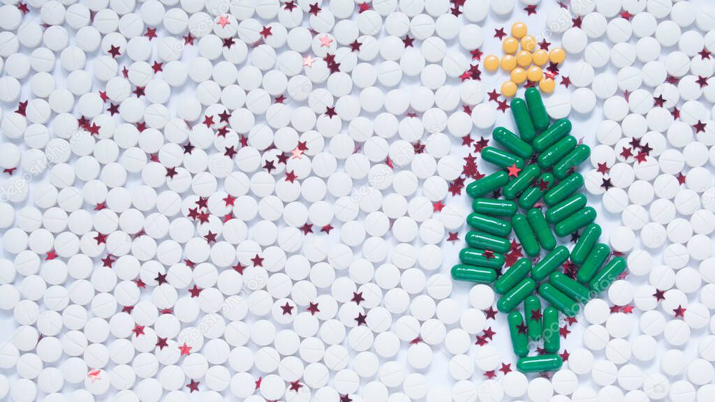 Christmas and Happy New Year theme for healthcare, medical and pharmacy concept. Green christmas tree, white snow and decorative yellow star made by medicine pill/capsule. Creative idea. Copy space.