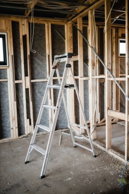 Açıkta duran kablolar, tahta kirişler ve merdiven ile inşa edilmiş bir ev.