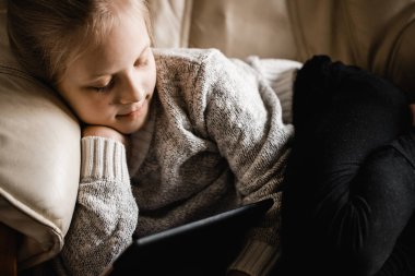 Kafkasya kökenli genç bir kız pencerenin kenarında oturup tabletindeki programları izliyor.