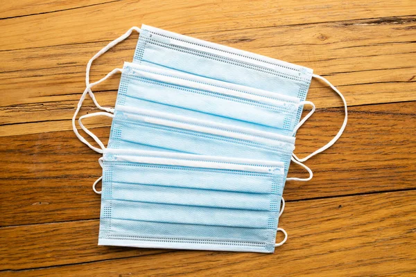 4 blue disposable surgical mask on a wooden background of PPE used during the corona virus COVID-19 pandemic