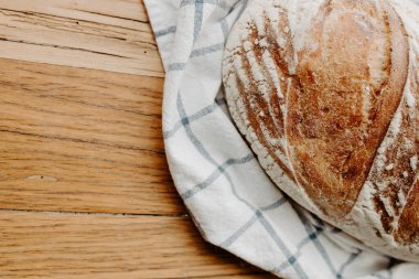 Ev yapımı hamurlu ekmek çay havlusunda soğuyor. Tahta bir tabakta, fotokopi alanı için yer var.