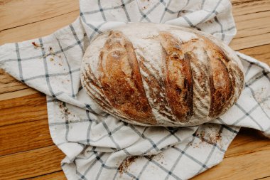 Ev yapımı hamurlu ekmek çay havlusunda soğuyor. Tahta bir tabakta, yabani çiçekler etrafa serpiştiriliyor.