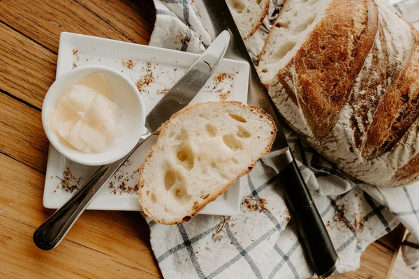 Beyaz bir tabakta tereyağlı bir dilim ekmek. Ev yapımı hamurlu ekmek. Çay havlusunda soğutuluyor.
