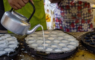 Tüccar bir çeşit Thai tatlısı yapıyor. Khanom Khrok. Havan topu kızartılmış hamur işi.. 
