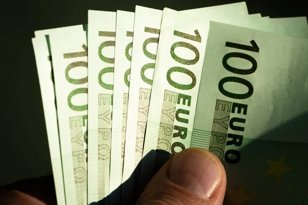 Several hundred Euro banknotes in the hands of a man. Euro close-up in a low key.