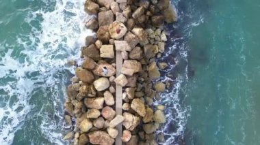 Dalgakıranın üzerinde duran balıkçıların hava manzarası.